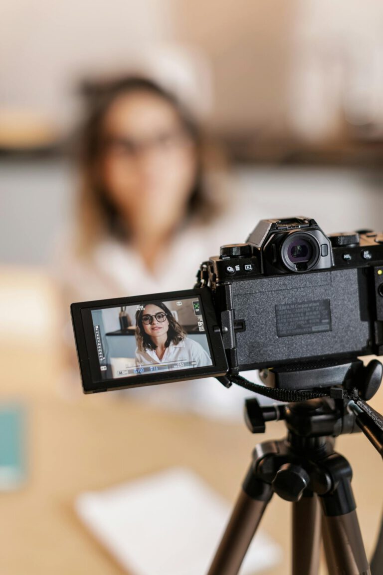 Woman recording video with DSLR camera, displaying on screen.